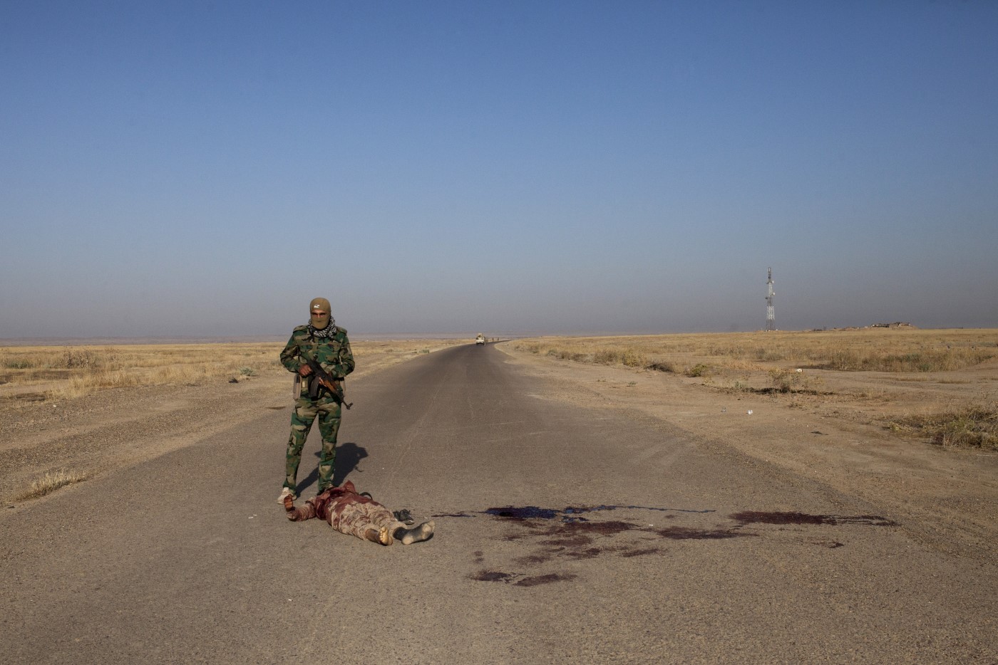 Peshmerga in front of the lifeless body of a member of the Islamic State a few minutes after the attack of the front line. Tuzkhurmatu, Kurdistan, Iraq. June 20, 2017
