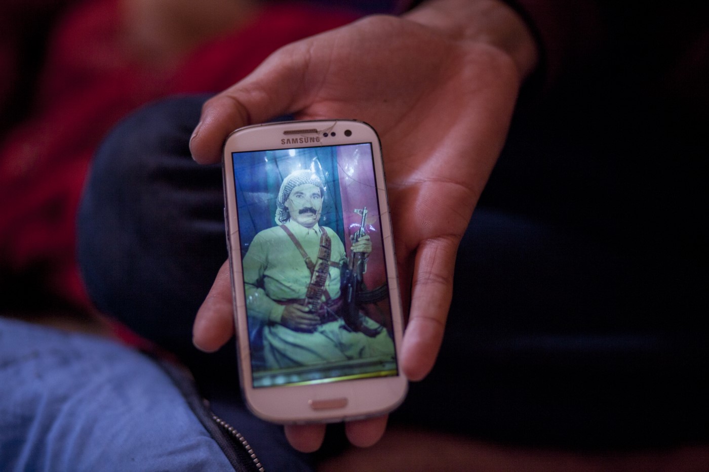 Baxtyar, a young Kurdish Iraqi refugee who had been a Peshmerga fighter against the IS, shows a photograph of his father (also Peshmerga) on his mobile phone. Refugee camp "Jungle", Dunkirk, France. May 4, 2016